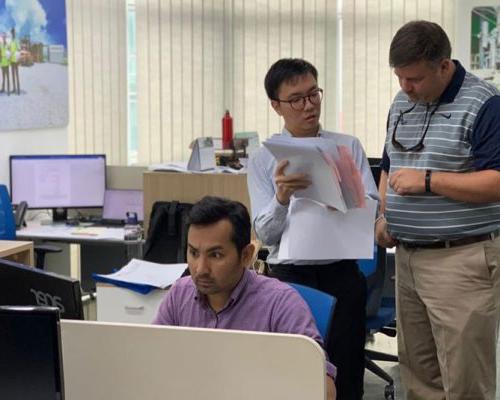 澳门足彩app员工在马来西亚办公室讨论项目文件